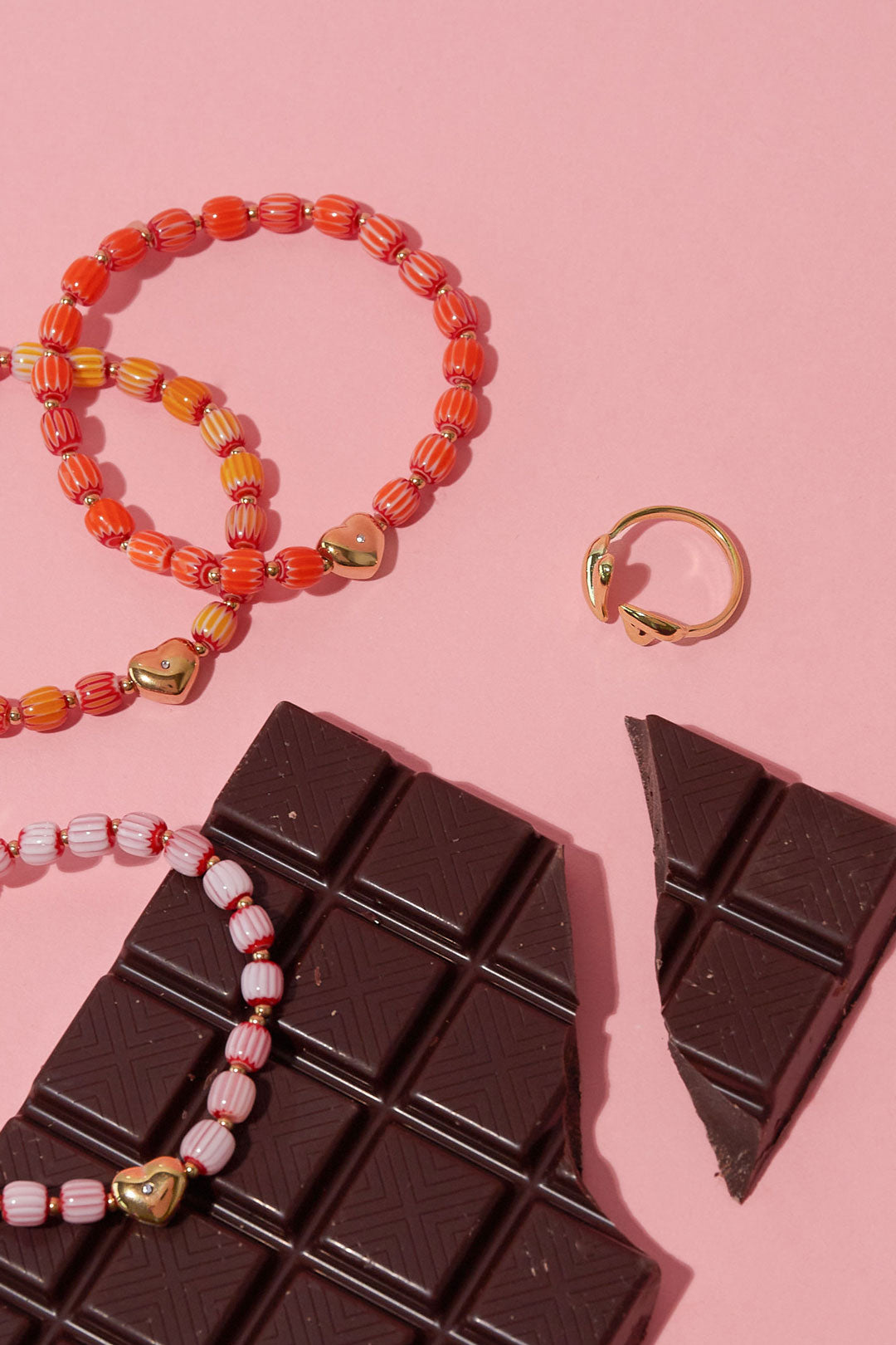 Verstelbare ring met speels gevormde hartjes - goud - naast een reep chocola en armbandjes