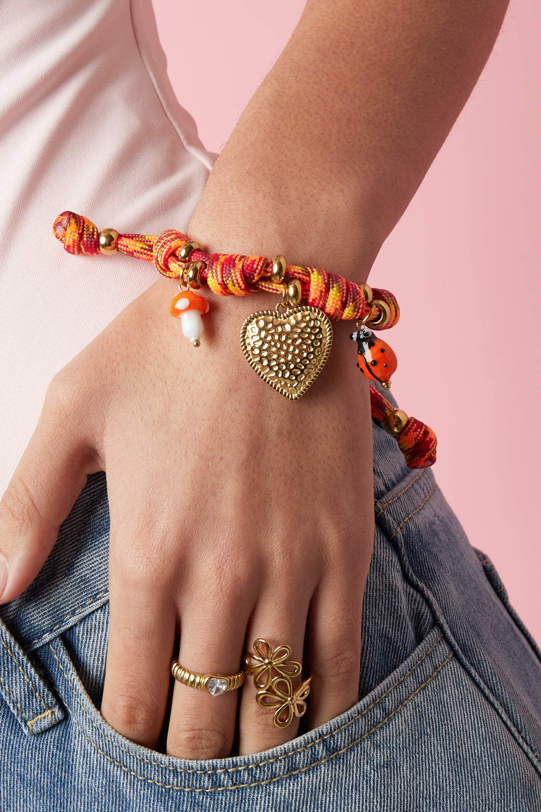 Armbanden met touwbedeltjes in de vorm van een hartje, gedragen om de arm van een model