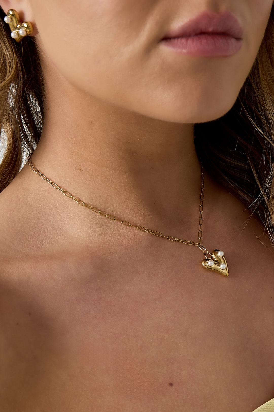 Ketting met hangend hartje en parels - gedragen om de hals van een model ingezoomd 