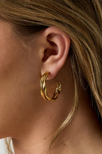 Organische dubbele oorringen - goud - gedragen in het oor van een model ingezoomd