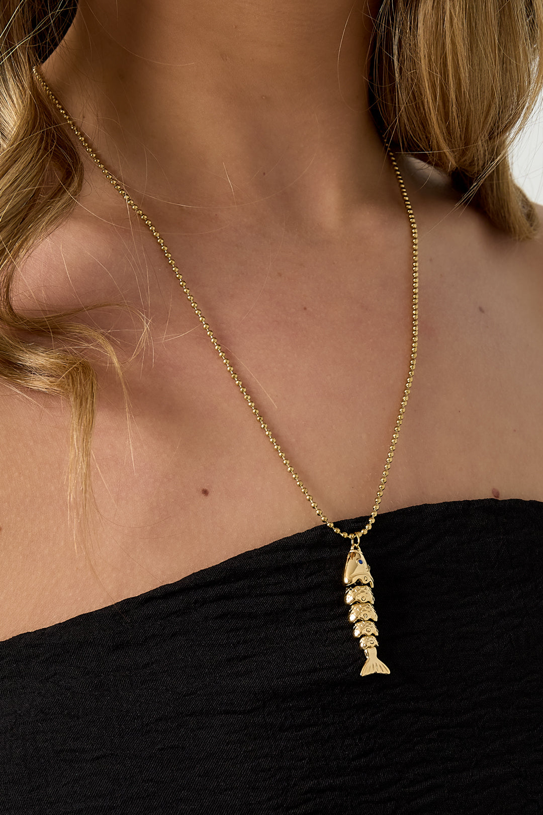 Ketting met bewegend visbedeltje - goud - gedragen om de hals van een model ingezoomd